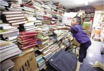 ??  ?? Cristian Orjuela, 5, looks for a book at Jose Alberto Gutierrez’s home.