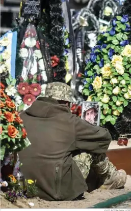  ?? OLEG PETRASYUK / EFE ?? Un soldado ucraniano junto a la tumba de un compañero en Kiev.