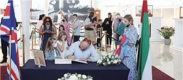  ?? Reuters ?? ↑ People write in a book of condolence following the passing of Queen Elizabeth at the Queen Elizabeth 2 floating hotel reception centre in Dubai.