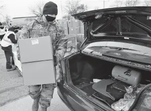  ?? TONY DEJAK/ASSOCIATED PRESS FILE PHOTO ?? Staff Sgt. Mike Schuster loads two boxes of produce into a car at a food distributi­on in January by the Greater Cleveland Food Bank. Nonprofits, especially those that rely on in-person events like arts and culture organizati­ons, have taken a major financial hit during the pandemic.