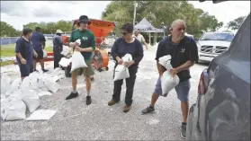  ?? CHRIS O’MEARA/AP help ?? MEMBERS OF THE TAMPA, FLA., PARKS AND RECREATION DEPT., residents load sandbags on Monday in Tampa, Fla.