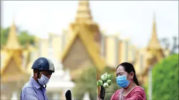  ?? AFP ?? A couple wearing facemasks as protection against Covid-19 in front of the Royal Palace.