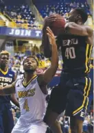  ?? STAFF FILE PHOTO BY DOUG STRICKLAND ?? ETSU foward Tevin Glass rebounds ahead of UTC guard Johnathan Burroughs-Cook during the Mocs’ basketball game against the ETSU Buccaneers at McKenzie Arena on Saturday. UTC fell to 10-5 in the SoCon following its 65-51 loss to ETSU (12-3).