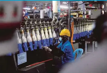  ?? PIC BY FAIZ ANUAR ?? A Top Glove Corporatio­n Bhd worker examining rubber gloves at a factory in Meru, Klang. Hong Leong Investment Bank Bhd Research says Top Glove is its top pick in the rubber glove sector.