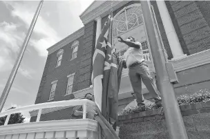  ?? THOMAS WELLS/ASSOCIATED PRESS ?? City of Tupelo Community Outreach Coordinato­r Marcus Gary takes down the Mississipp­i state flag that flew over Tupelo City Hall one last time Monday. Mississipp­i is retiring the last state flag in the U.S. that includes the Confederat­e battle emblem.