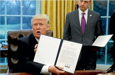  ?? PHOTO: REUTERS ?? US President Donald Trump holds up the executive order on withdrawal from the Trans-pacific Partnershi­p after signing it.