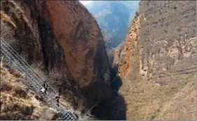  ?? JIANG HONGJING / XINHUA ?? Left: Residents of the last group of households in Atulieer village atop a cliff in Liangshan Yi autonomous prefecture, Sichuan province, descend the 4 kilometers of steel stairs and move to a newly built community on May 13, 2020.