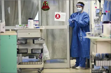  ?? JULIE BENNETT — THE ASSOCIATED PRESS ?? A nurse puts on rubber gloves before entering a COVID-19 patient’s room in East Alabama Medical Center’s intensive care unit Dec. 10 in Opelika, Ala. Doctors and nurses try to cope while caring for COVID-19 ahead of the holidays.