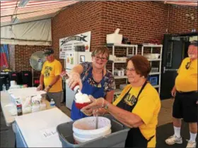  ?? BILL DEBUS — THE NEWS-HERALD ?? Jane Carle, left, and Marilyn Raishart prepare a strawberry treat for a customer on June 17 at the Kirtland Kiwanis Strawberry Festival.