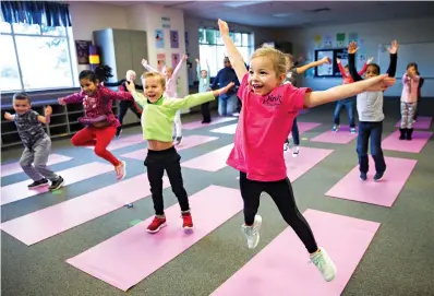  ?? Ashley Landis/The Dallas Morning News via AP ?? ■ Charlotte Mayer, right, and other kindergart­en students participat­e in a yoga class Jan. 24 at Pink Elementary in Frisco, Texas.