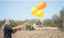  ?? Photo / Getty Images ?? A Palestinia­n supporter of the Al-Nasir Salah Al-Din Brigades prepares incendiary balloons to launch into Israel.