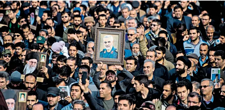  ??  ?? A demonstrat­or holds a picture of Qassim Soleimani, the Iranian military commander killed by a US drone strike, aloft as thousands of Iranians take to the streets to mourn the ‘glorious martyr’