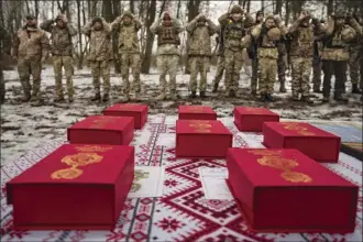  ?? AP photo ?? Medals are placed on a table as Ukrainian servicemen of the Prince Roman the Great 14th Separate Mechanized Brigade adjust their hats before a flag ceremony where some of them were honored for their bravery and accomplish­ments in battle, in the Kharkiv area, Ukraine, Saturday, Feb. 25, 2023.