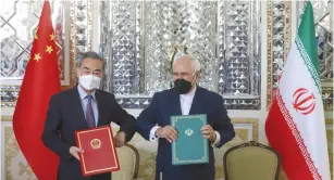  ?? (Majid Asgaripour/WANA (West Asia News Agency) via Reuters) ?? IRANIAN FOREIGN Minister Mohammad Javad Zarif (right) and Chinese Foreign Minister Wang Yi bump elbows during the signing ceremony of a 25-year cooperatio­n agreement in Tehran earlier this year.