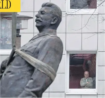  ?? JOHN MACDOUGALL / AFP / GETTY IMAGES ?? A resident watches as a statue of former Soviet dictator Josef Stalin is lifted by a crane in Berlin Tuesday. The statue stood for 15 minutes before being moved, to promote an exhibition in the German capital called Stalin, The Red God.