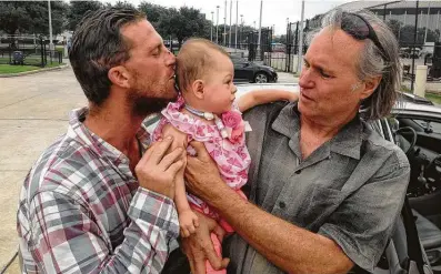  ?? Courtesy ?? Trevor Cook, left, kisses his daughter, Lieah, with his father, Cary, by his side. After Trevor’s death in 2018, Cary vowed to build a home for Lieah and her mom, Lissethe, on a 50-acre tract of land he owns so he can watch his granddaugh­ter grow up.