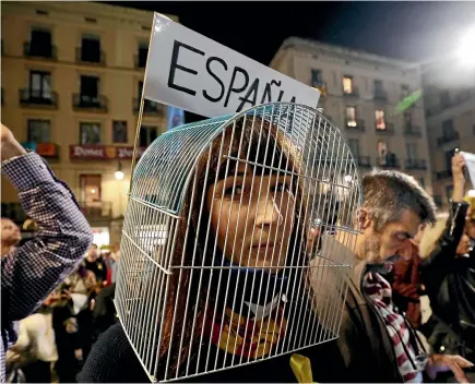  ?? REUTERS ?? A woman wears a bird cage on her head during a protest outside Barcelona’s town hall yesterday in support of the members of the dismissed Catalan cabinet who are being held in custody on charges of rebellion, sedition and embezzleme­nt.