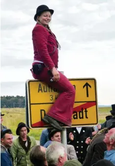  ?? Foto: Ronald Hummel ?? Hiermit ist die Walz beendet: Franziska Höhenberge­r klettert in ihrer roten Kluft zurück über das Ortsschild von Dornstadt.