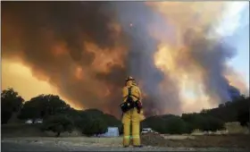  ?? KENT PORTER — THE PRESS DEMOCRAT VIA AP ?? A tower of smoke pours from Cow Mountain as Burney, California firefighte­r Bob May keeps a watch on surroundin­g vegetation for spot fires during a wildfire off Scotts Valley Road, Thursday near Lakeport