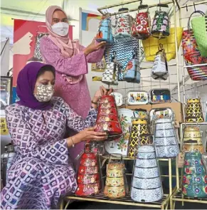  ?? — Filepic ?? tiffin Jeiwa founder and director Ina Fadilah Nizar (seated) and employee Nurnadira Syuhada Mohamad Zim with various kinds of food containers and baskets.