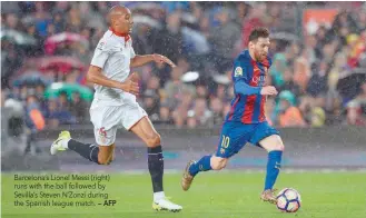 ?? — AFP ?? Barcelona’s Lionel Messi (right) runs with the ball followed by Sevilla’s Steven N’Zonzi during the Spanish league match.