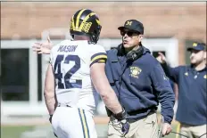  ?? HOLLY HART — THE ASSOCIATED PRESS ?? Michigan coach Jim Harbaugh talks with Ben Mason during the first half of an NCAA college football game against Illinois, Saturday in Champaign, Ill.