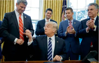  ?? AP ?? President Donald Trump hands a pen to Representa­tive Bill Huizenga after signing House Joint Resolution 41 in the Oval Office of the White House in Washington. House Speaker Paul Ryan, Representa­tive Sean Duffy and Representa­tive Peter King are...