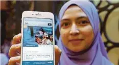  ??  ?? KAKITANGAN KPWKM Wan Fatimah Najwa Wan Shaari menunjukka­n portal MANIS di telefonnya.