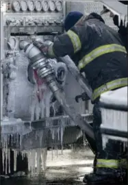  ??  ?? A Newark, N.J., firefighte­r labors through ice while disconnect­ing hoses off an engine after helping battle a five-building fire Jan. 5.