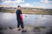  ??  ?? Ciudad Juárez resident Jesus Jaquez watches his son and other children take a dip in the Rio Grande to cool off in an area that borders New Mexico on Tuesday. He’s among residents who believe the deployment of the National Guard will improve border security in the area, which is a busy smuggling corridor.