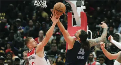  ?? (AP/Jess Rapfogel) ?? Washington center Kristaps Porzingis (left) battles for a rebound with Memphis center Steven Adams in the Wizards’ 102-92 victory on Sunday in Washington. Porzingis scored a game-high 25 points on 7-of-15 shooting.