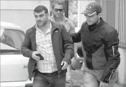  ?? GEORGIA PANAGOPOUL­O/AFP-GETTY IMAGES ?? Greek journalist Kostas Vaxevanis, left, is escorted by plain-clothed police officers to the public prosecutor in Athens on Sunday, following his arrest after publishing names from a list of Greeks with Swiss bank accounts in his magazine.