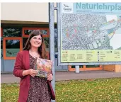  ?? FOTO: W. WALTER ?? Alina Gries mit ihrem Buch am Naturlehrp­fad am Schulzentr­um, sie hat früher das Gymnasium dort besucht.
