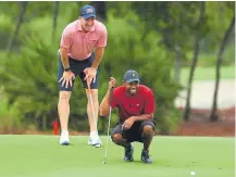  ??  ?? Tiger Woods and former Broncos quarterbac­k Peyton Manning laugh while Woods reads a putt on the sixth green on Sunday in Hobe Sound, Fla.