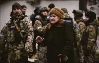  ?? Vadim Ghirda / Associated Press ?? A woman walks by Ukrainian servicemen shortly after a convoy of military and aid vehicles arrived in the formerly Russian-occupied Kyiv suburb of Bucha, Ukraine, Saturday.