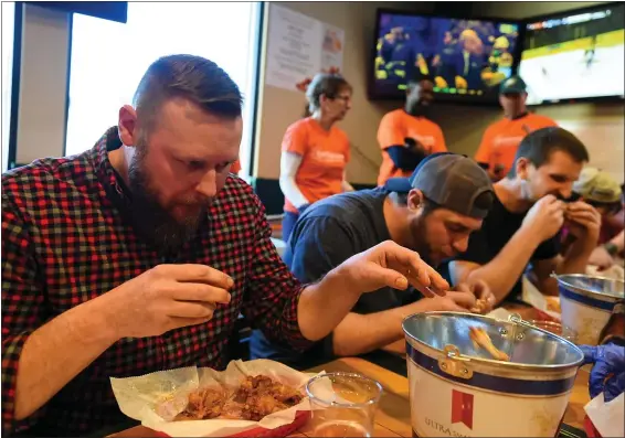  ?? SUSAN L. ANGSTADT — FOR MEDIANEWS GROUP ?? Pete Ludwig, left, from one of the Glass & Sons Collison teams, chows down during Sunday’s 28th annual Easterseal­s wing-eating contest at California Bar & Grill in Cumru Township. The event raised over $18,000 to help send special-needs kids to Camp Lily.
