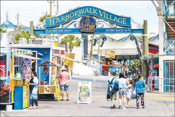  ?? ?? The Harborwalk Village in Emerald Grande Coast is filled with people walking and shopping, buying food in cafes and street vendor restaurant­s.