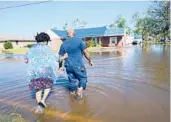  ?? GERALD HERBERT/AP 2020 ?? Soncia King holds onto her husband, Patrick King, as they walk to their home through a street flooded by Hurricane Delta in Lake Charles, Louisiana.