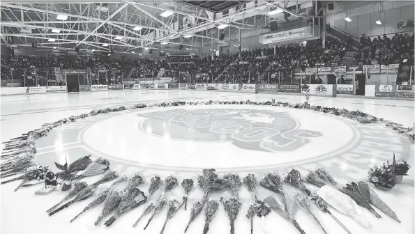  ?? JONATHAN HAYWARD/THE CANADIAN PRESS ?? Flowers were placed at centre ice April 8 as people gathered for a vigil at the Elgar Petersen Arena, home of the Humboldt Broncos.
