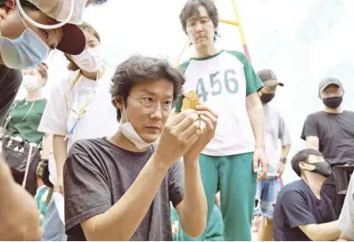  ?? ?? A behind-the-scenes photo from the making of Netflix’s Squid Game shows series creator and director Hwang Dong Hyuk (seated) and lead star Lee Jung Jae (standing, looking on). Hwang and Lee won the Emmy for drama series directing and top acting prize, respective­ly.