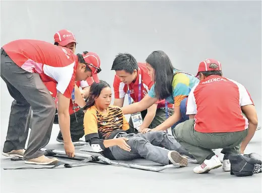  ?? -Gambar Bernama ?? CHRISTINA dibantu anggota paramedik setelah mengalami kecederaan ketika sesi pemanasan diri sebelum memulakan pusingan akhir acara Park Wanita Sukan Asia 2018 di Stadium Papan Selaju Bandar Sukan Jakabaring.