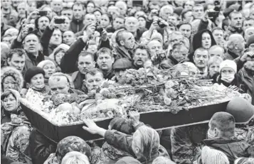  ?? JEFF J MITCHELL, GETTY IMAGES ?? The body of an anti- government demonstrat­or who was killed in clashes with police is carried through Independen­ce Square on Saturday in Kiev, Ukraine.