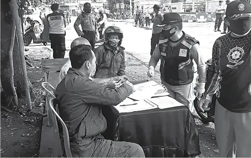  ?? ARISKI PRASETYO/JAWA POS ?? BUKAN MASKER: Salah seorang pengendara terjaring razia di Jalan Dukuh Kupang. Dia berusaha mengakali petugas dengan memakai penutup wajah. Bukan dengan masker.