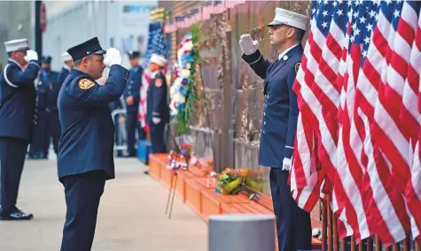  ?? AP ?? New York City firefighte­rs salute in front of a memorial on the side of a firehouse adjacent to One World Trade Centre and the 9/11 Memorial site during ceremonies on the anniversar­y of 9/11 terrorist attacks in New York yesterday.