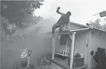  ?? JUSTIN SULLIVAN, GETTY IMAGES ?? A resident rushes to save his home Monday as a wildfire races through Glen Ellen, Calif. Tens of thousands of acres and dozens of homes and businesses have been burned in Napa and Sonoma counties.