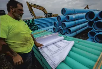  ?? MONICA CABRERA/THE MORNING CALL ?? Mike Gardner, utility supervisor for contractor Leon E. Wintermyer Inc., unrolls site plans for the 810,000-square-foot manufactur­ing plant.