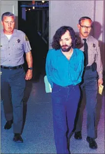  ?? Associated Press ?? CHARLES MANSON, center, is escorted to court in L.A. in August 1970 during the trial in the Tate-LaBianca murders.