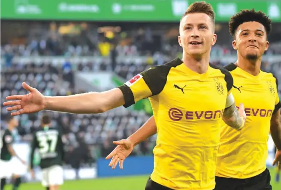  ??  ?? Dortmund’s Marco Reus, left, celebrates his side’s opening goal during the match against VfL Wolfsburg Photo: AP