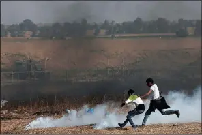  ?? AP/ADEL HANA ?? Palestinia­n protesters try to pick up tear-gas canisters to throw back at Israeli soldiers during clashes Friday along Gaza’s border with Israel.