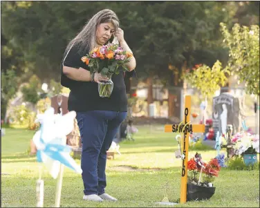  ?? (AP/Gary Kazanjian) ?? Lori Gonzalez wipes a tear away after visiting the temporary grave marker of her sister and Kaiser Permanente Fresno Medical Center nurse Sandra Oldfield, pictured right, at the Sanger Cemetery in Sanger, Calif.